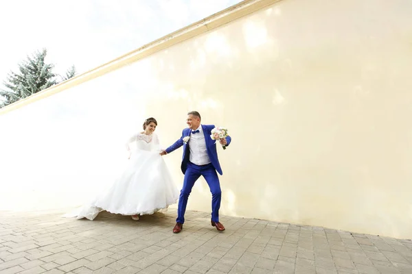 Superbes jeunes mariés par mur beige — Photo