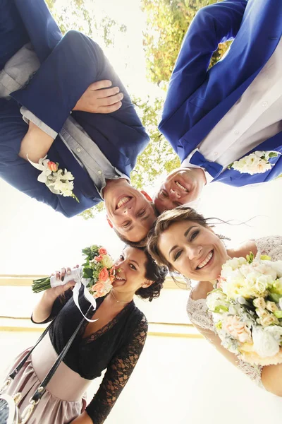 Nygifta och vänner bockning till kameran — Stockfoto