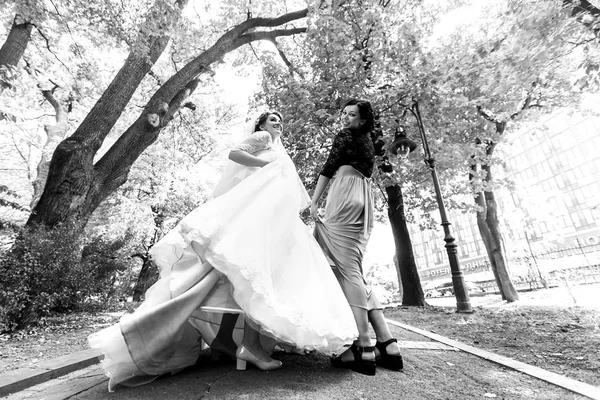 Mariée et demoiselle d'honneur posent dans le parc — Photo