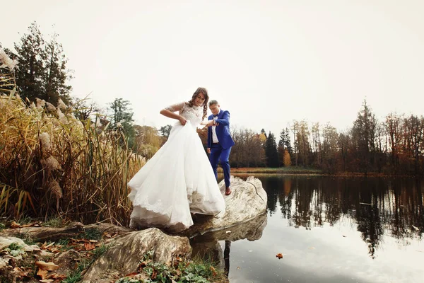 Hermosa pareja de boda por el lago de otoño — Foto de Stock