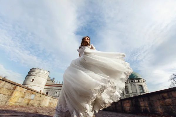 Bride in magnificent dress by old castle — Stock Photo, Image