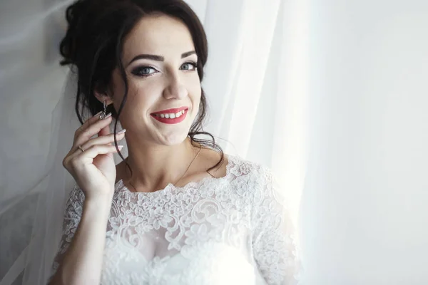 Elegant bride in lace gown by window — Stock Photo, Image