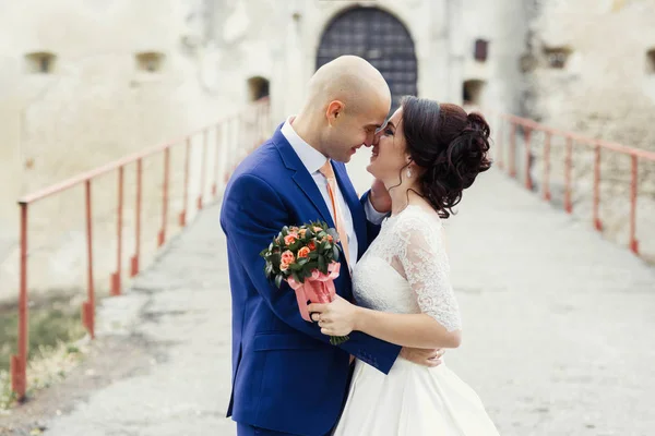 Heureux jeunes mariés sur une promenade par le vieux château — Photo