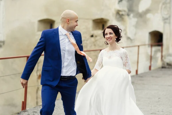 Heureux jeunes mariés sur une promenade par le vieux château — Photo