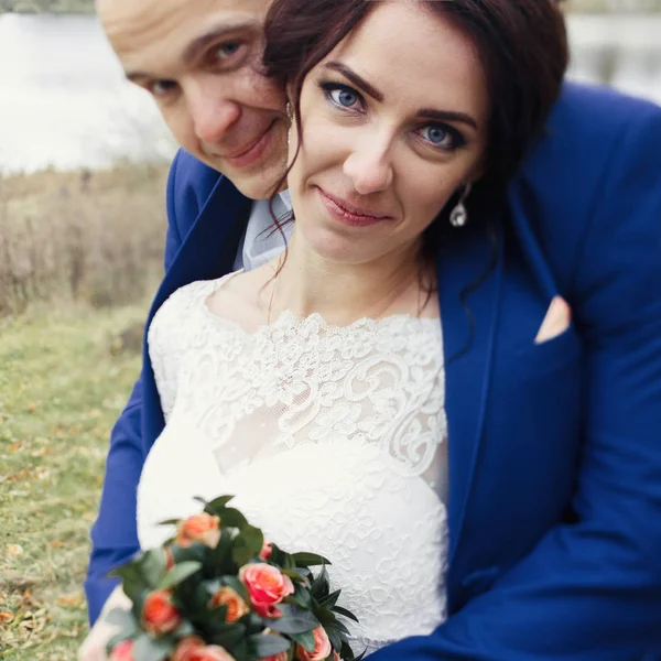 Recém-casados abraçando por lago de outono — Fotografia de Stock