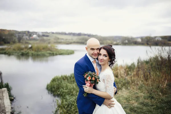 Mariés embrassant par lac d'automne — Photo