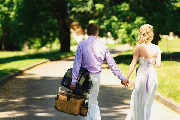 Recém-casados no parque com cesta para piquenique — Fotografia de Stock