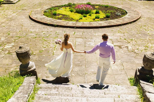 Hochzeitspaar spaziert durch Blumenbeet — Stockfoto