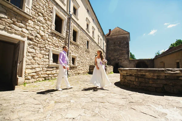 Wedding couple walking by old castle — Stock Photo, Image