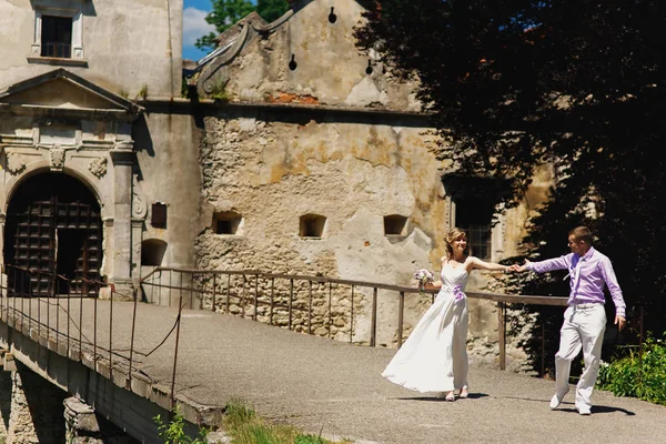 Wedding couple walking by old castle — Stock Photo, Image