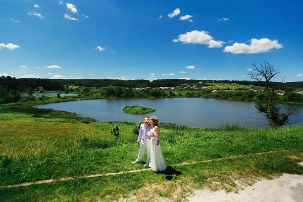 Wedding couple standing on the green hill — Stock Photo, Image