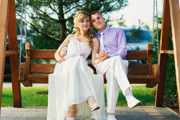 Groom and bride on wooden swing — Stock Photo, Image