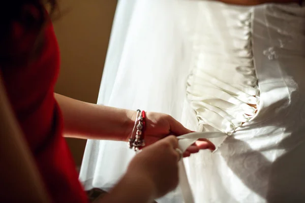Женщина шнурки корсет на невесте — стоковое фото