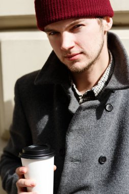 Adam sokakta kahve ile kırmızı şapkalı 