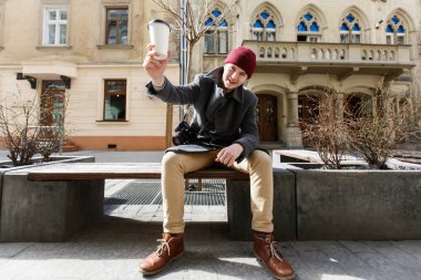 Adam sokakta kahve ile kırmızı şapkalı 