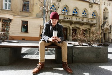 Adam sokakta kahve ile kırmızı şapkalı 