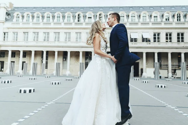 迷人的新婚夫妇看起来奢华的穿着优雅的礼服在巴黎浪漫的街道上 — 图库照片