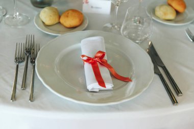 Kırmızı kurdele yalanlar üzerine yemek tabağı ile süslenmiş beyaz peçete