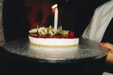 Gümüş tepsi üzerinde tek bir mum ile lezzetli peynirli kek standları