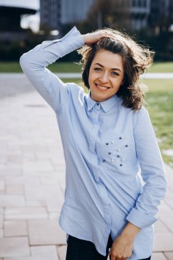 Mutlu kız mavi tişört ve kot dışında teşkil etmektedir ve saçlarını güneşli bir günde sallar