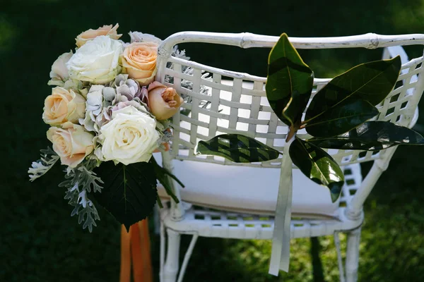 白色和橙色婚礼花束放在白色花园椅上 — 图库照片