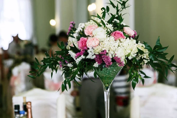 丰富的玫瑰和粉红色的花束放在一个玻璃花瓶站在餐桌上 — 图库照片