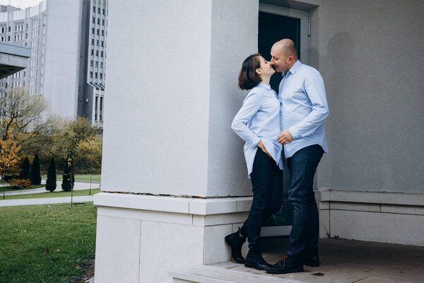 Kissing couple poses on the footstep before a grey building