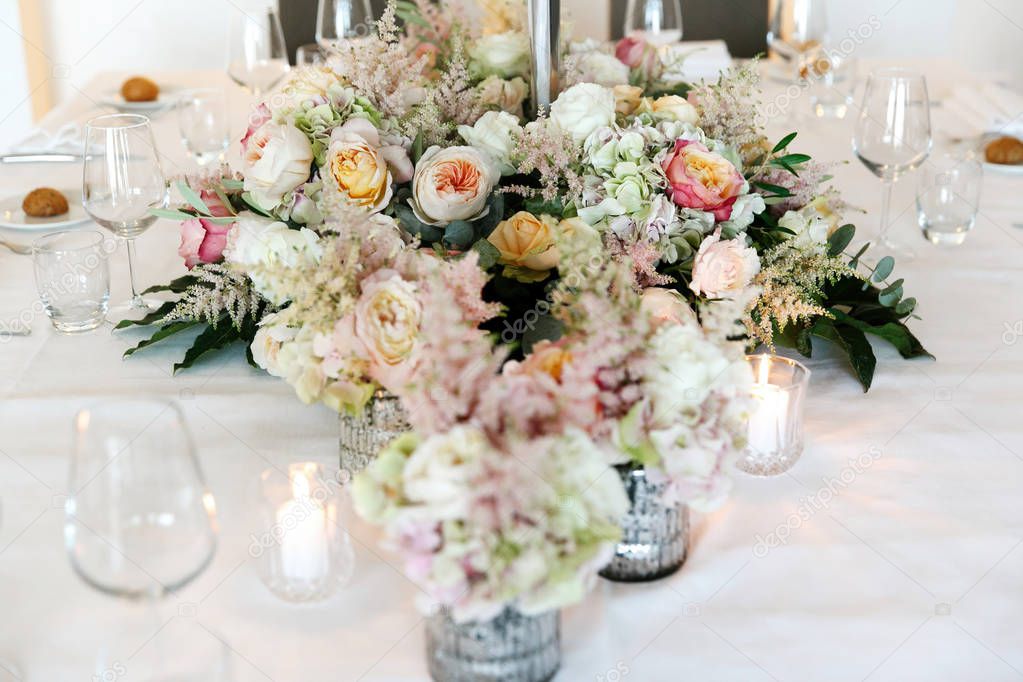 Dinner table decorated with rich pink and white roses and peonies with fern leaves