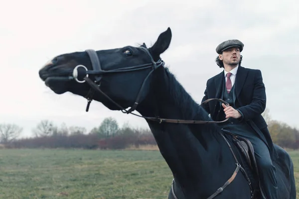 Caucasian Man Wearing Black Suit Tweed Blinder Riding His Horse Stock Picture