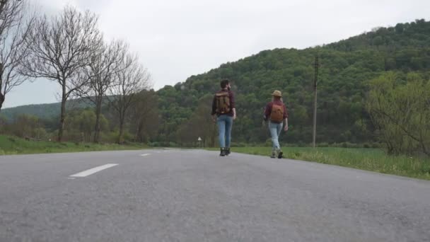 Pareja camina a lo largo de la carretera y mira el coche — Vídeos de Stock