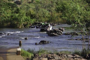 Kununurra, Avustralya - 8 Kasım 2010. Ivanhoe Kavşağı 'na park etmiş bir kamyonet ve nehirde yüzen insanlar, Kununurra, Batı Avustralya, Avustralya. Ord Nehri üzerinde beton bir geçit..