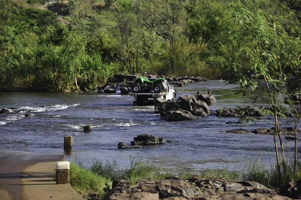 Kununurra, Avustralya - 8 Kasım 2010. Ivanhoe Kavşağı 'na park etmiş bir kamyonet ve nehirde yüzen insanlar, Kununurra, Batı Avustralya, Avustralya. Ord Nehri üzerinde beton bir geçit..