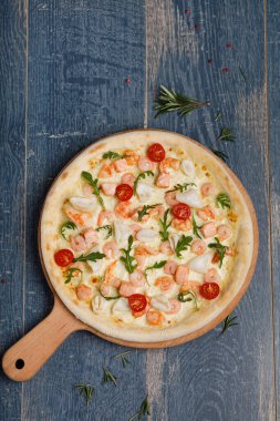 Somonlu pizza ve mavi ahşap arka planda kiraz.