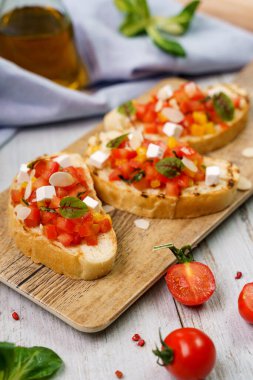Domatesli bruschetta ve tahta tabakta keçi peyniri.