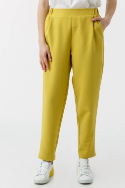 Beyaz arka planda sarı pantolonlu genç bayan.