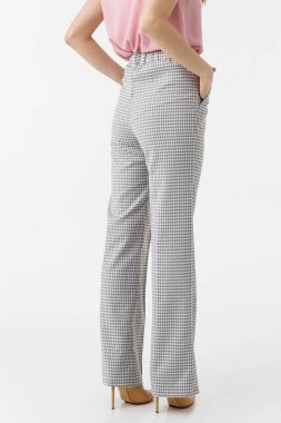 Beyaz arka planda gri pantolonlu genç kız.