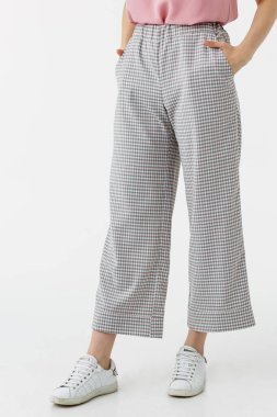 Beyaz arka planda gri pantolonlu genç kız.