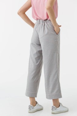 Beyaz arka planda gri pantolonlu genç kız.