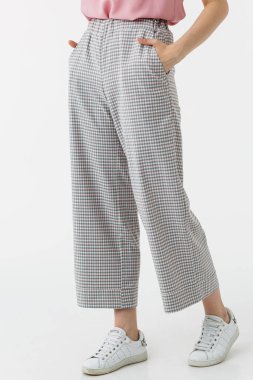 Beyaz arka planda gri pantolonlu genç kız.