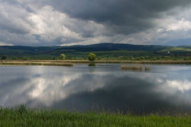 Panoramik göl Rotbav, tepeler üzerinde bir güneşli bahar günü bulutlu mavi gökyüzü Rotbav, Romanya, Europe ile arka planda ile turizm tesisi için