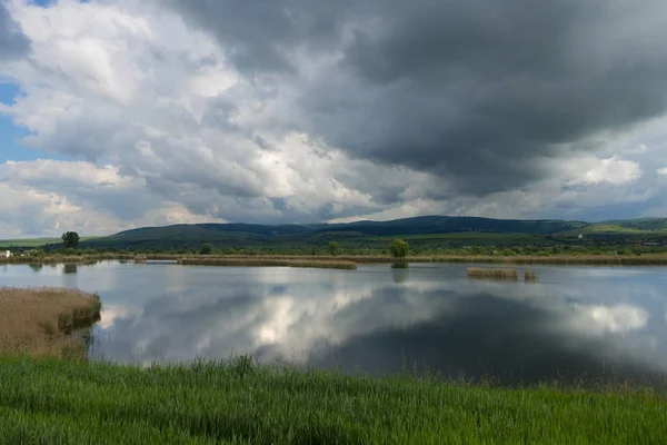 호수 Rotbav, 흐린 푸른 하늘 Rotbav, 루마니아, 유럽으로 화창한 봄 날에 배경에서 힐스 관광 리조트 파노라마 보기 — 스톡 사진