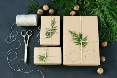 Koyu arka plan üzerinde rustik Eko Noel paketleri kahverengi kağıt, dize ve doğal çam dalları ile kaydırma