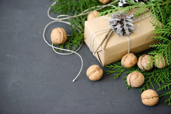 Wrapping rustic eco Christmas packages with brown paper, string and natural fir branches on dark background — Stock Photo, Image