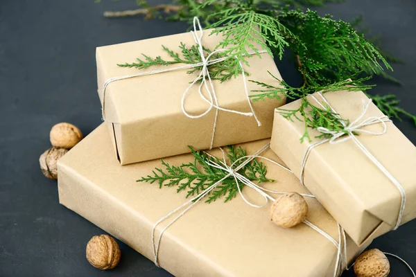 Lovely Holiday wrapping ideas rustic eco Christmas packages with brown paper, string and natural fir branches on dark background