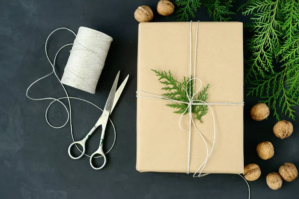 Envolvendo pacotes rústicos de Natal eco com papel marrom, cordas e ramos de abeto naturais no fundo escuro — Fotografia de Stock