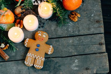 Zencefilli kurabiye adam mandalina, çam kozalakları, ceviz ve ahşap zemin, tatil dekorasyon üzerine mum Noel kompozisyonu