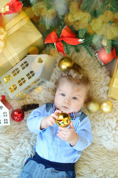 Aranyos kis baba portré ünnepel Karácsony. Újévi ünnepek. Boytie a fiú fekszik a fa alatt decoraction labdáztak — Stock Fotó
