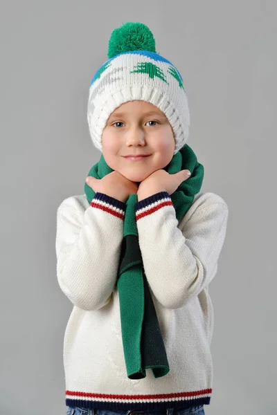 Fashionabla porträtt av en bedårande barn pojke i varm vintermössa och halsduk på grå bakgrund — Stockfoto