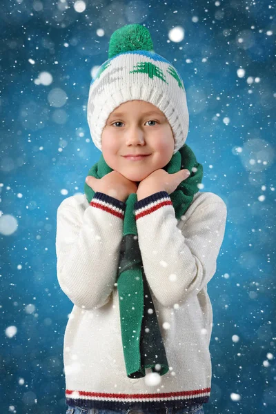 温暖的冬天的帽子和围巾上蓝色背景绘制雪花可爱的蹒跚学步的小男孩的肖像 — 图库照片