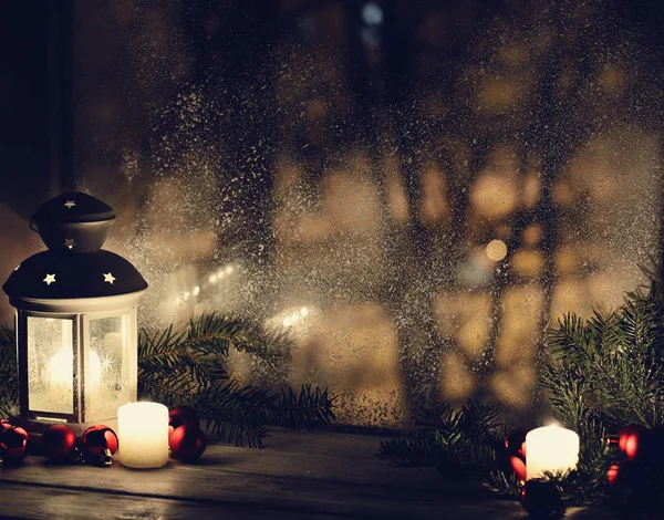 Kerst lantaarn met sneeuwval, kaarsen, weergeven van het venster op de straat van de nacht — Stockfoto